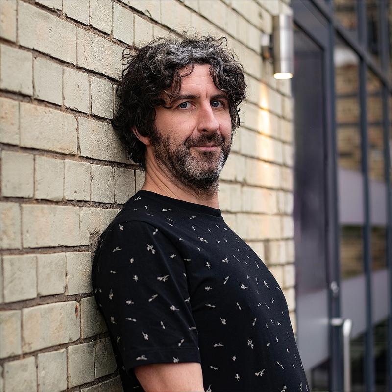 A man leaning against a brick wall.