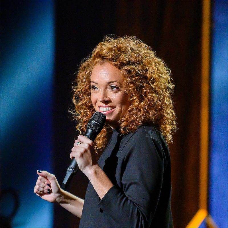 Photo of Michelle Wolf on stage holding a microphone.