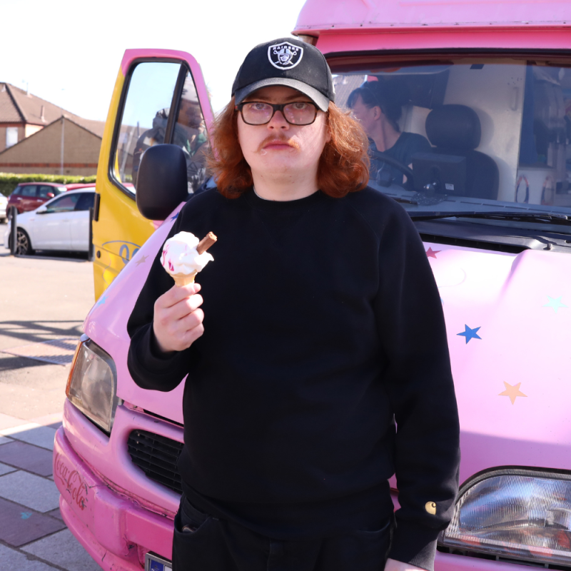 Jack stands in front of a pink van holding an ice cream cone.