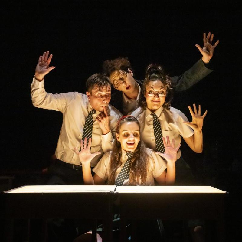 Four performers close together looking at an imaginary patisserie display