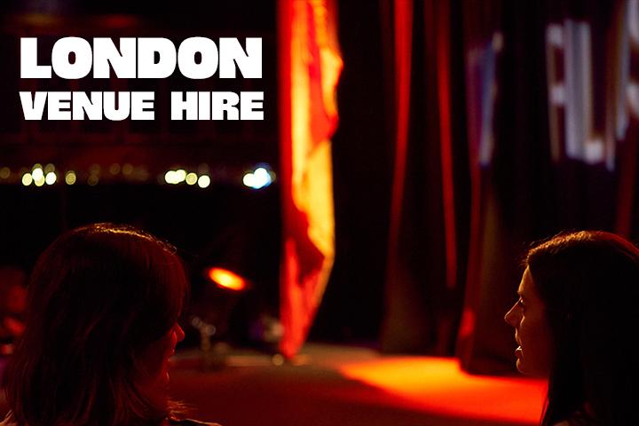 Two women sitting in the stalls in front of the stage, white text on the image reads "London Venue Hire"