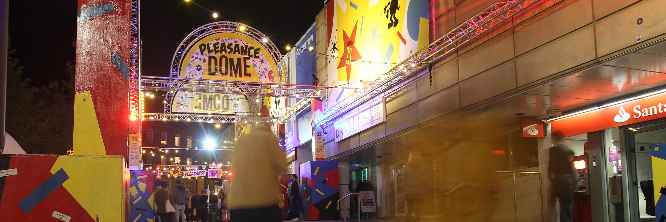 A time-lapse photo of the Dome entrance at night with a blur of people passing