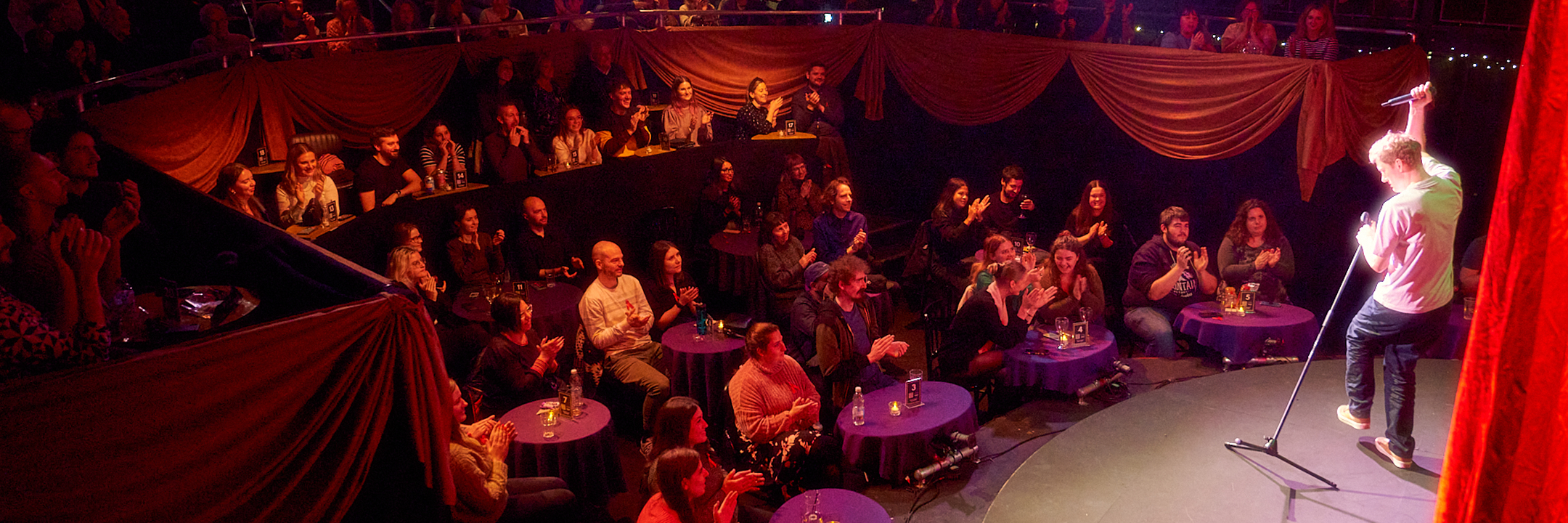 A photo of an audience watching a stand up perform in the Main House