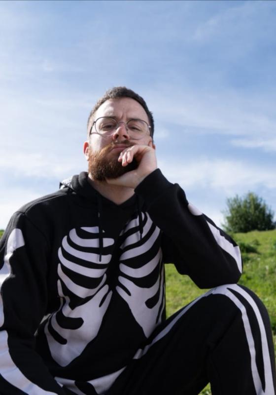 A person in a skeleton garment sitting on grass