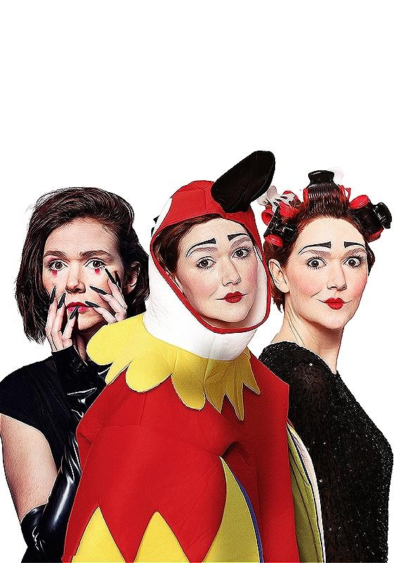 Elf Lyons (the clown) is dressed as a Raven, a Parrot and a woman in rollers. She looks inquisitively towards the camera. 