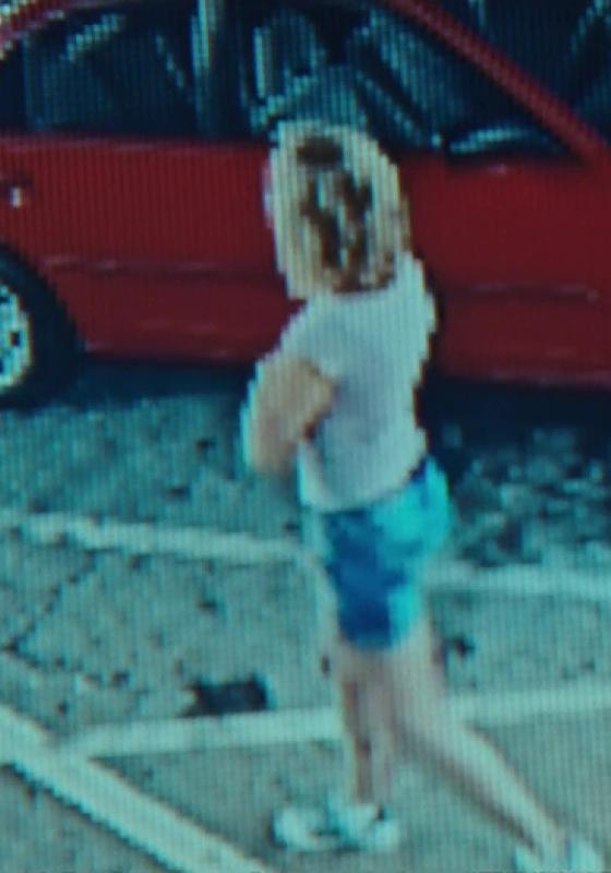CCTV of a woman in a car park beside a red car