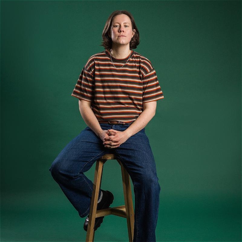 Chloe Petts sitting on a stool wearing jeans and a striped top