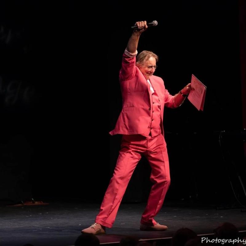 Mervyn Stutter on stage in pink suit