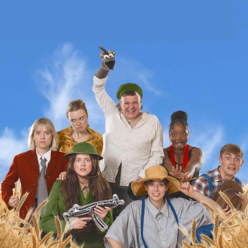 the cast among some tall grass, one with an emu puppet on their hand