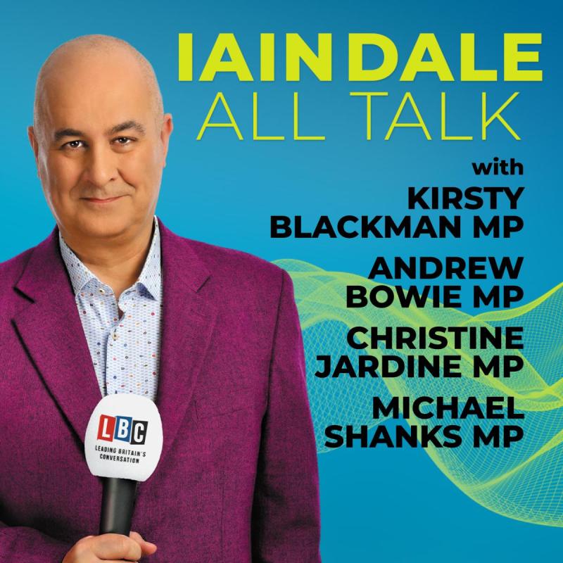 Iain Dale, a bald man in a purple suit, is holding a microphone in front of a blue background, with the title of the show and guests listed next to him.