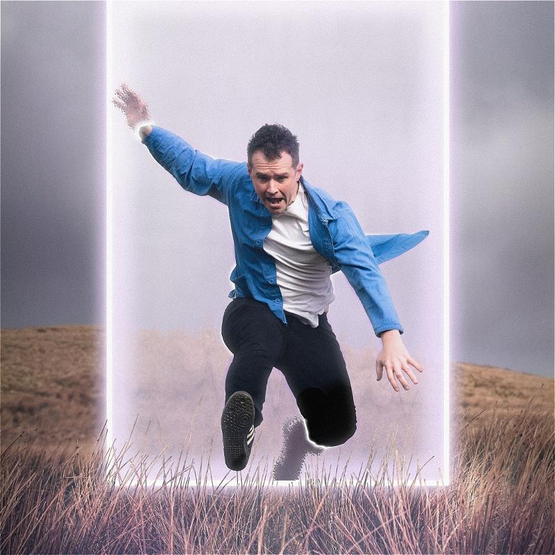 A person in a casual outfit mid-jump across a glowing portal in a grassy field.