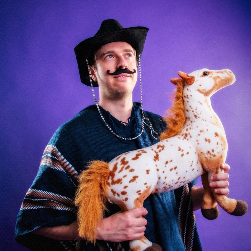 A person wearing a hat and a poncho holding a stuffed horse