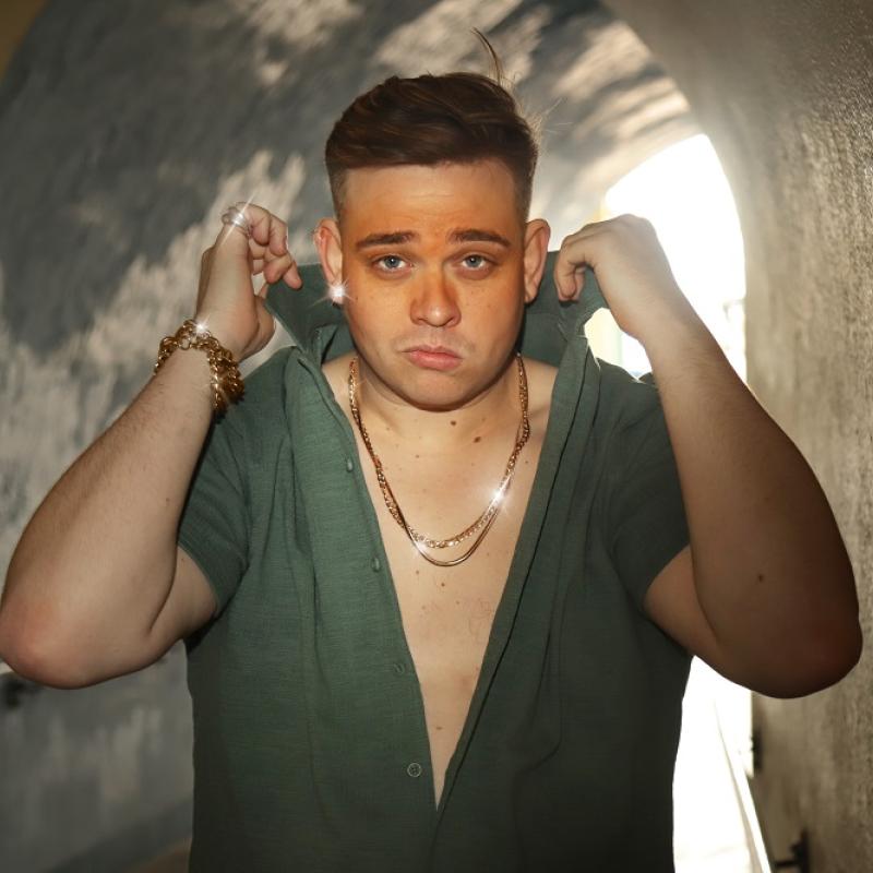 A person in a tunnel lifting the collar of his green shirt