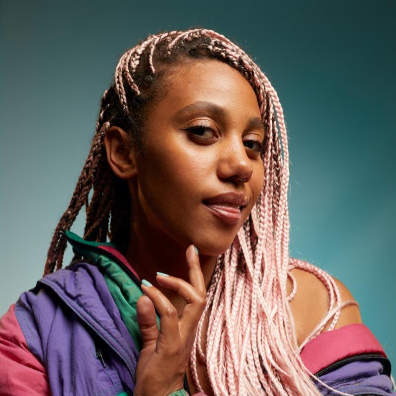 Image of Kate Cheka, performer, in front of a blue background