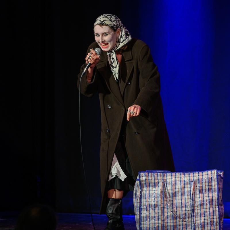 Image of Ozzy Algar, performer, onstage with a bag