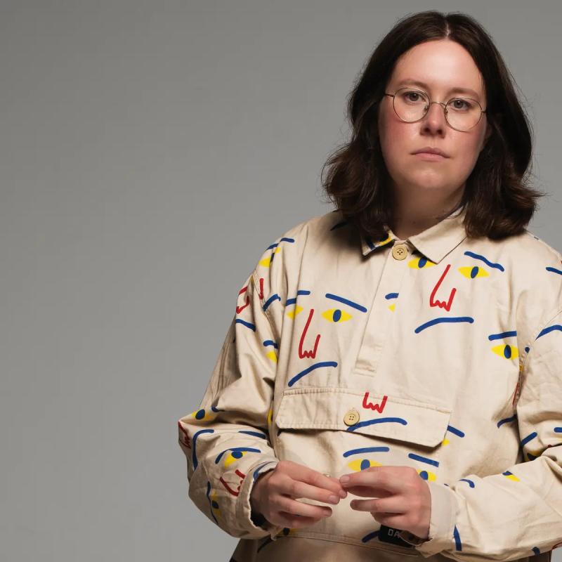 A person with glasses and a white shirt with a blue and yellow design