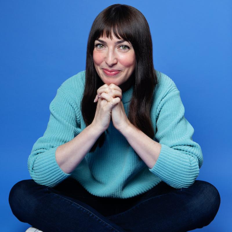 A person sitting cross legged with her hands folded together