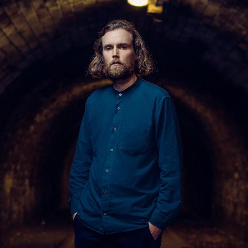 A person with long hair and beard in a dark tunnel