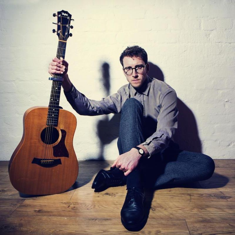 A person sitting on the floor with a guitar