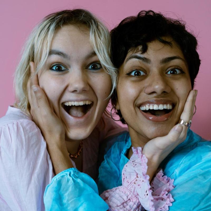 Two women smiling and holding their cheeks