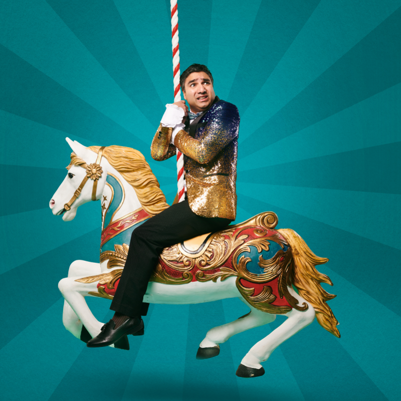 Nick sitting on a carousel horse looking over his shoulder in alarm