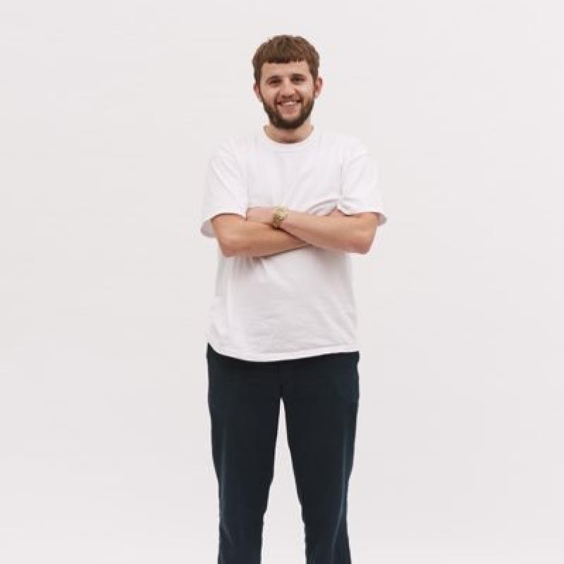 Rory smiling and standing with his arms crossed against a plain white background